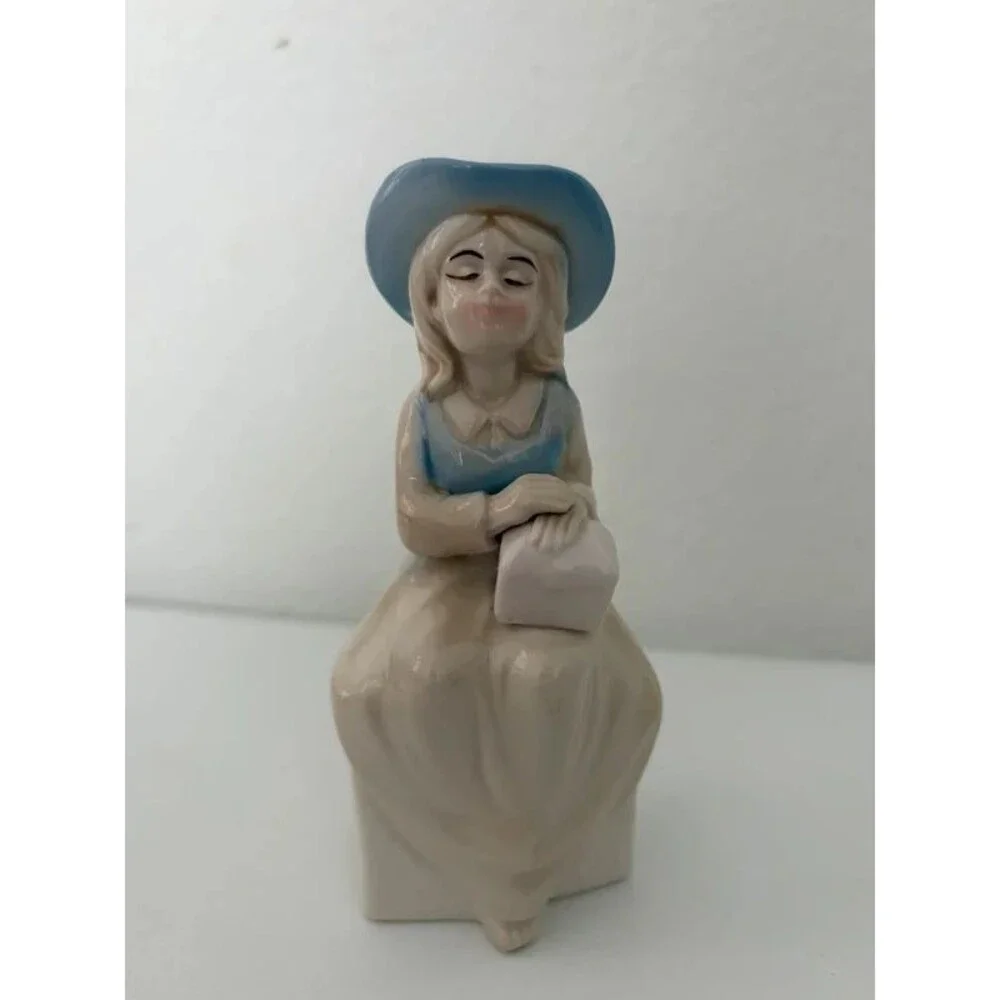 vtg. porcelain figurine of a seated girl wearing a blue hat